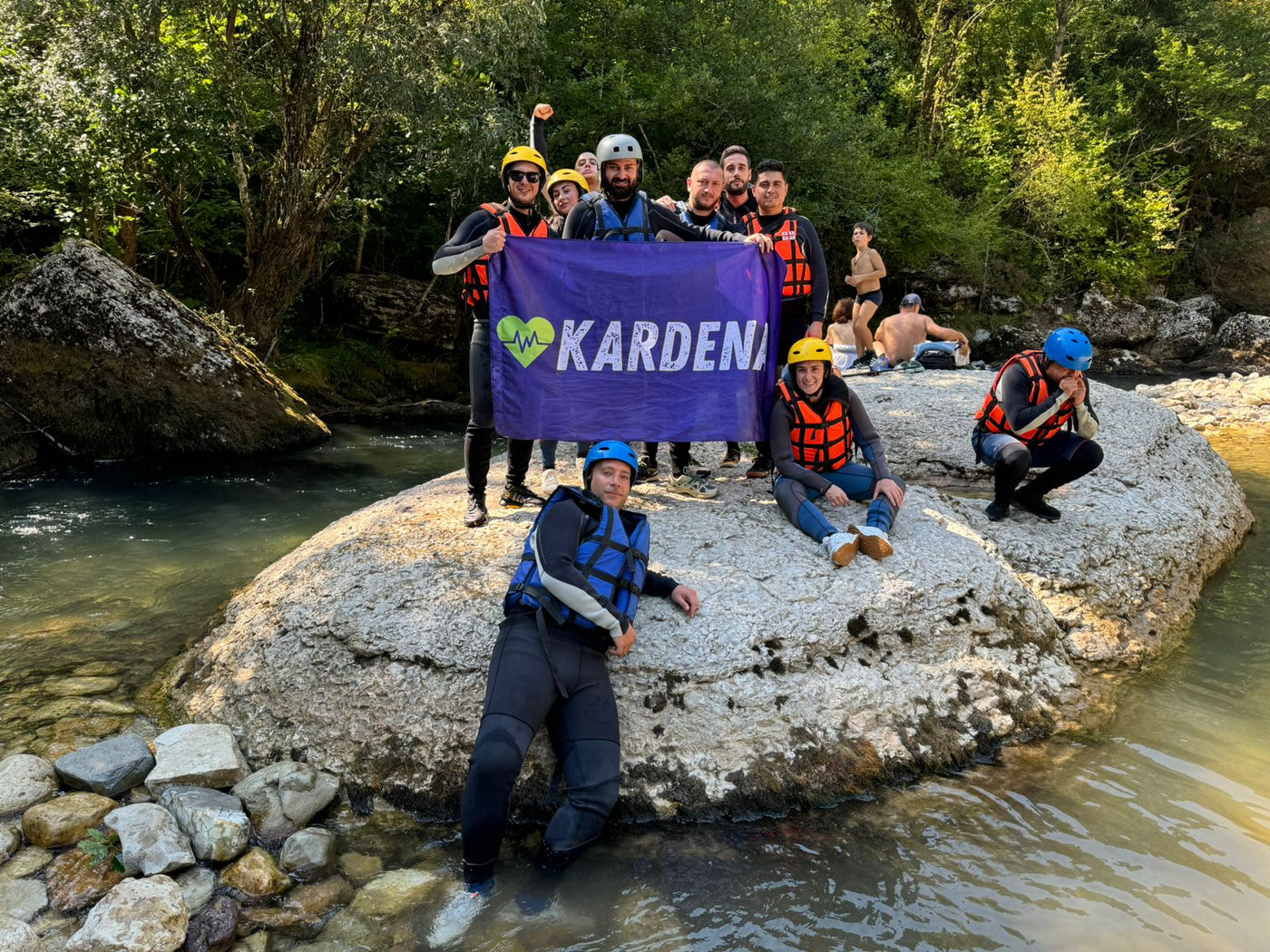 Gruppe mit Kardena-Flagge am Fluss, in Outdoor-Ausrüstung für Abenteuer und Gesundheit